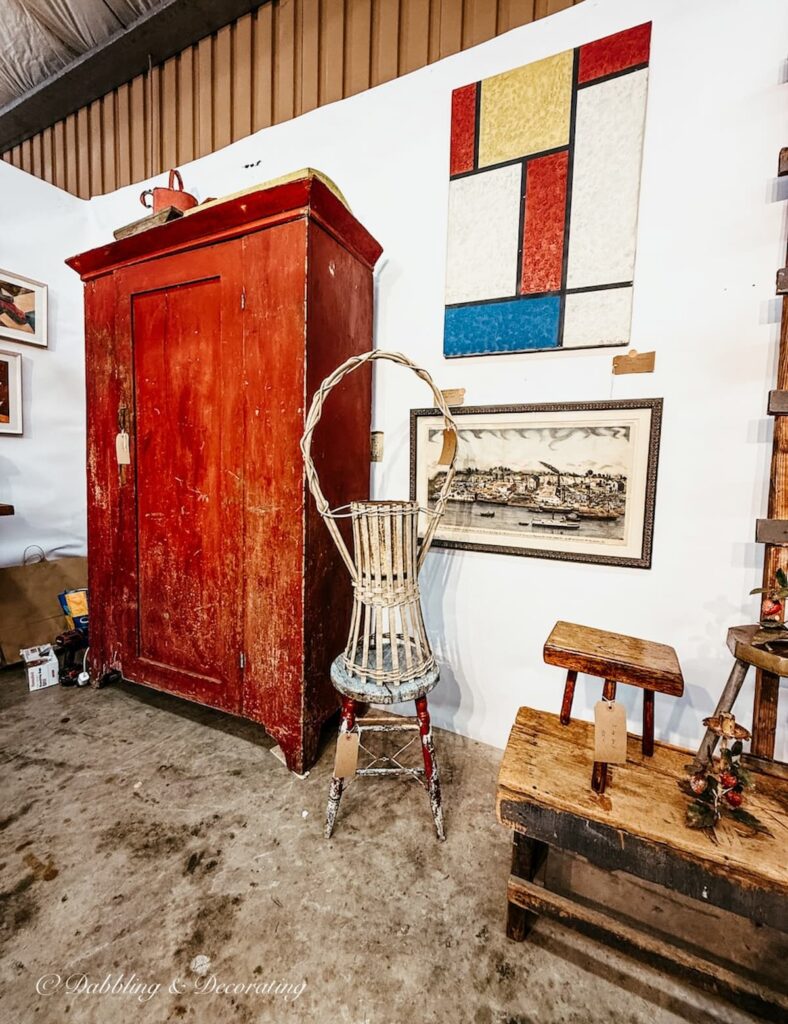 High end antique booth with large primitive red hutch and wall art at the Taconic Antiques Fair in NY.