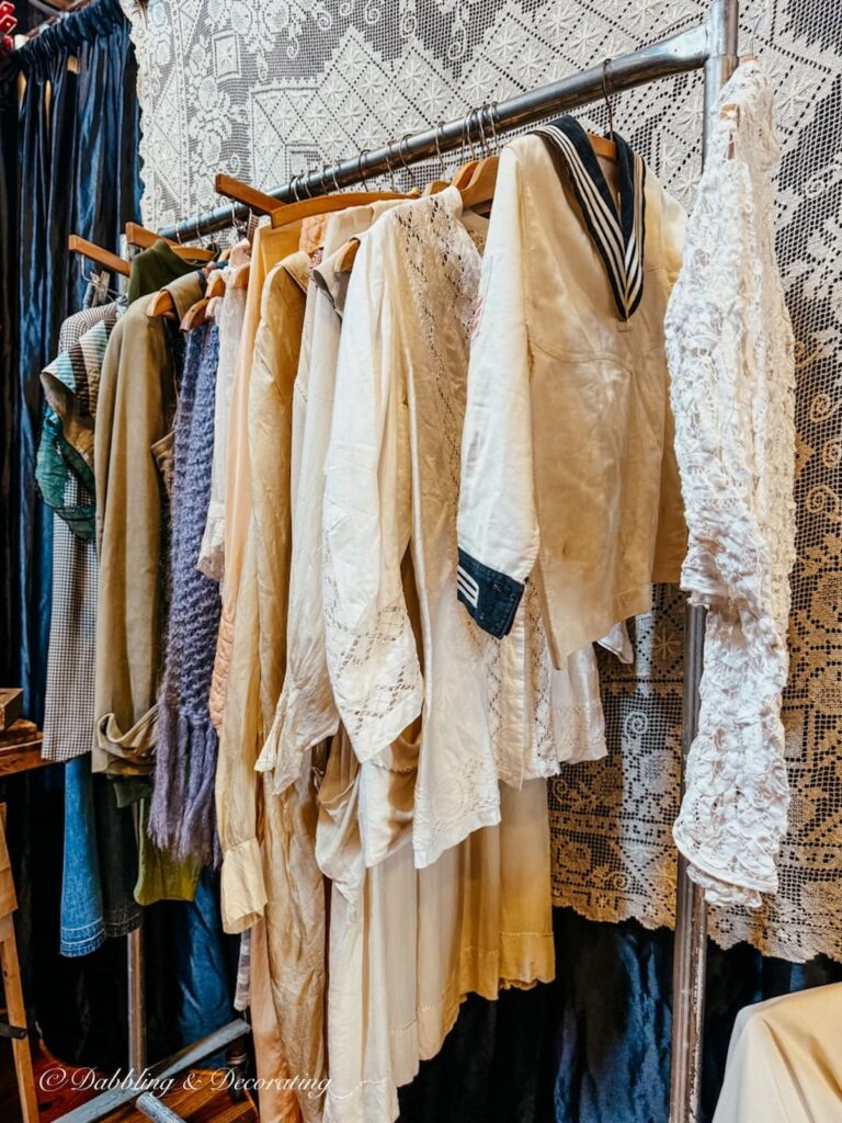 Rack of antique clothing at Taconic Antiques Fair inside vintage booth display.