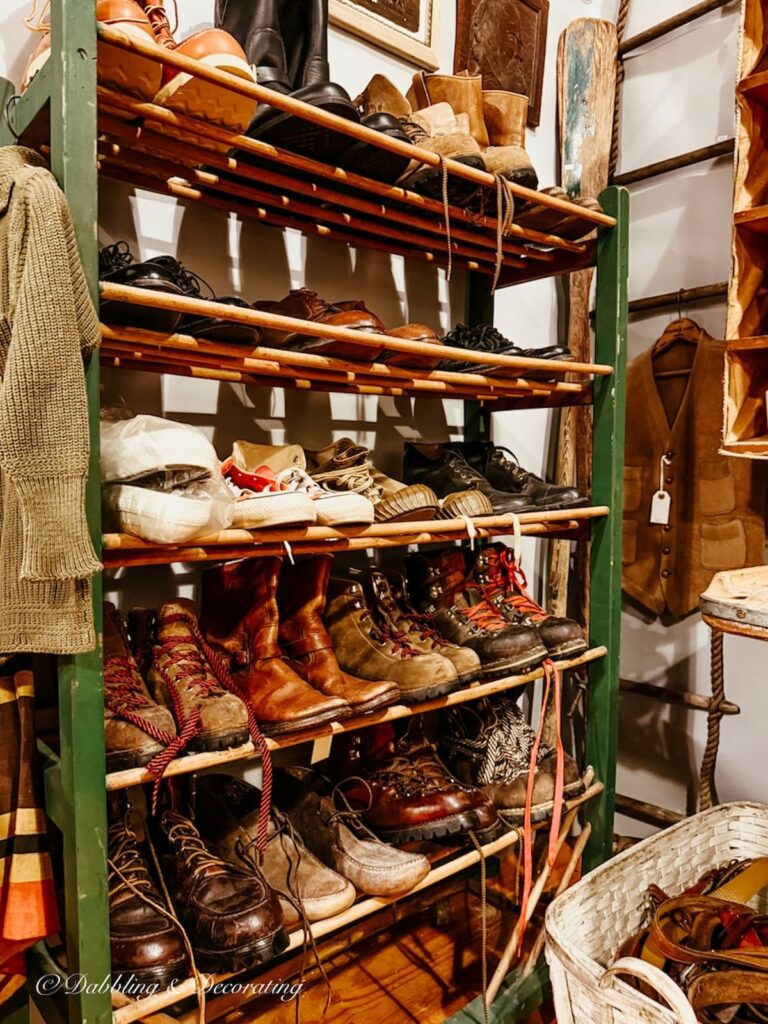 Vintage cobbler rack filled with vintage shoes and boots inside antique booths at Taconic Antiques Fair.