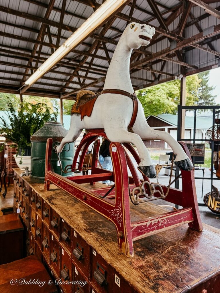 Beautiful white carousel horse on red stand standing tall inside an High-End Antique Booths.