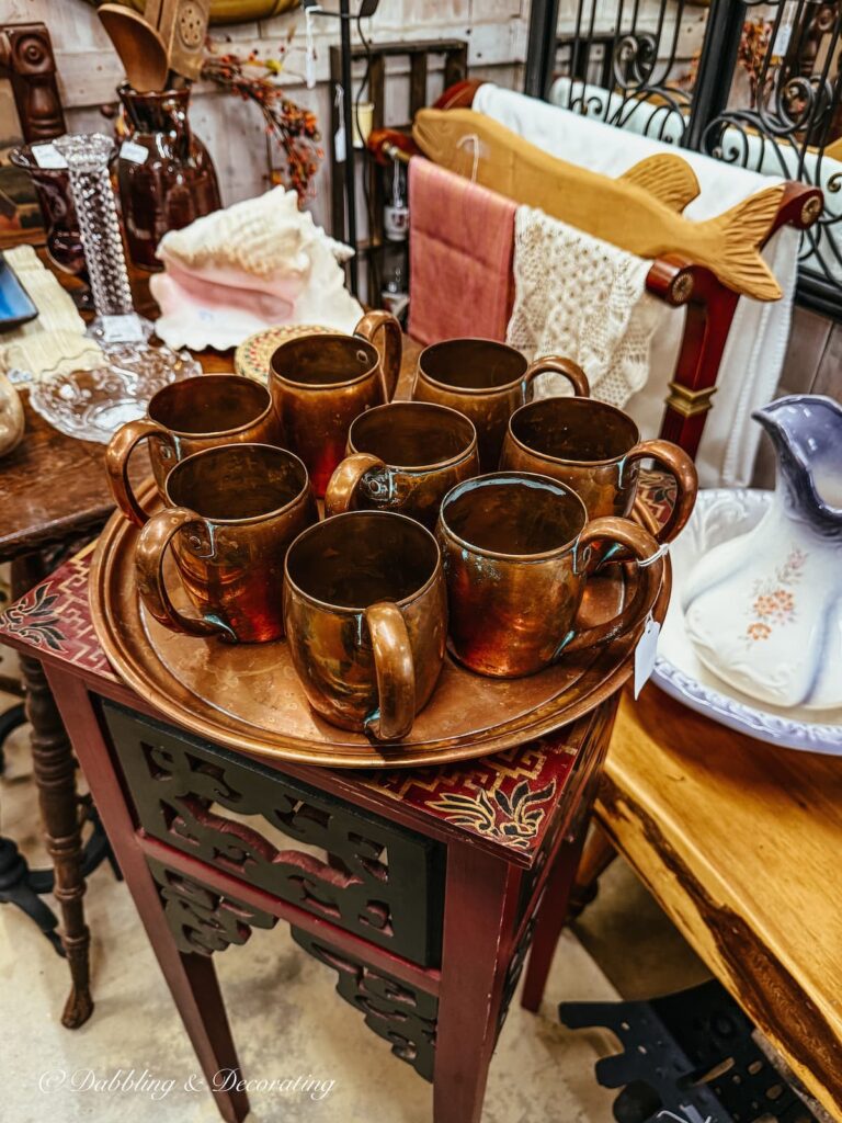 Copper tray and 9 vintage copper mugs inside Stone House Antique Center in Vermont.