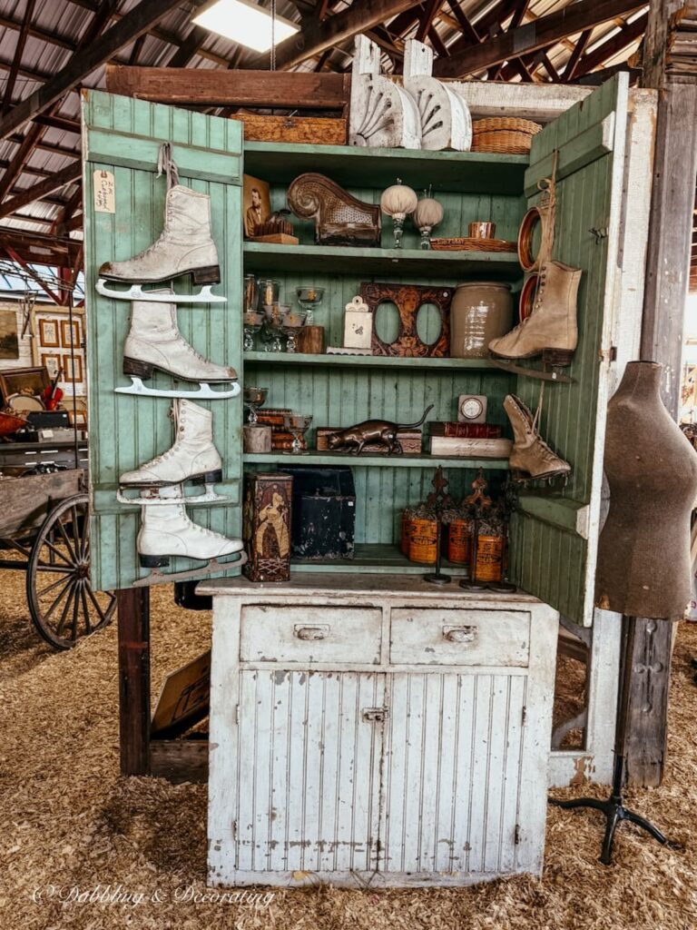 Vintage aqua cabinet filled with antiques open doors and ice skates lined up on the door. LOVE!
