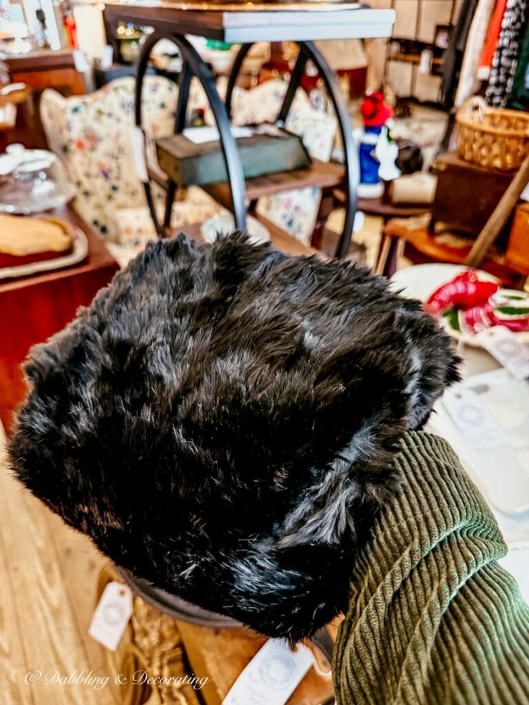 Thrifted black muff in hand at antique store.
