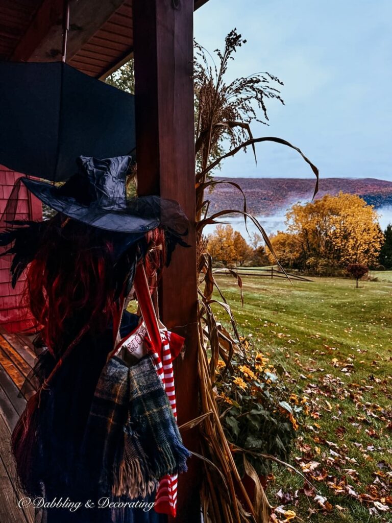 Mannequin witch styled on front porch with misty morning mountain views during peak fall foliage.