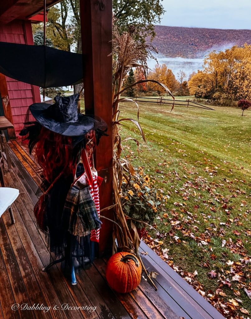 Halloween Witch Porch Ideas on a rainy day in the mountains with a mannequin witch and pumpkin on porch.