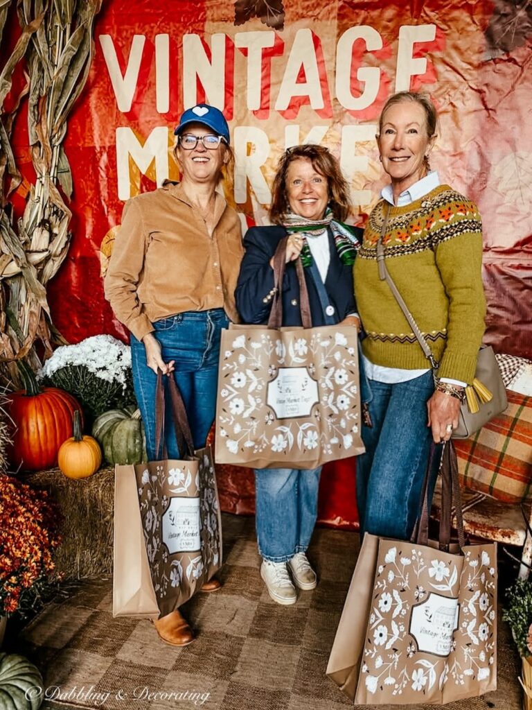 Three women in front of the Vintage Market Days sign in Vermont with Vintage Market Days Bags.
