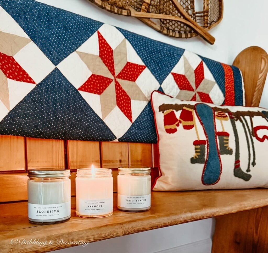 3 Hayden Rowe Candes; Vermont, First Tracks, and Slopeside scents on a vintage church pew accessorized with vintage quilt, ski lodge pillow and vintage snowshoes in entryway.