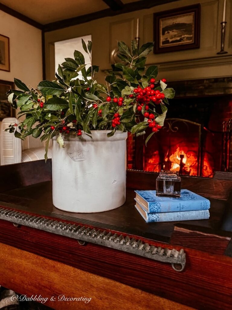 Vintage crock decorating ideas with winterberries in a cozy Sunday home vibe with winterberries on a living room antique coffee table and a fire in the fireplace.